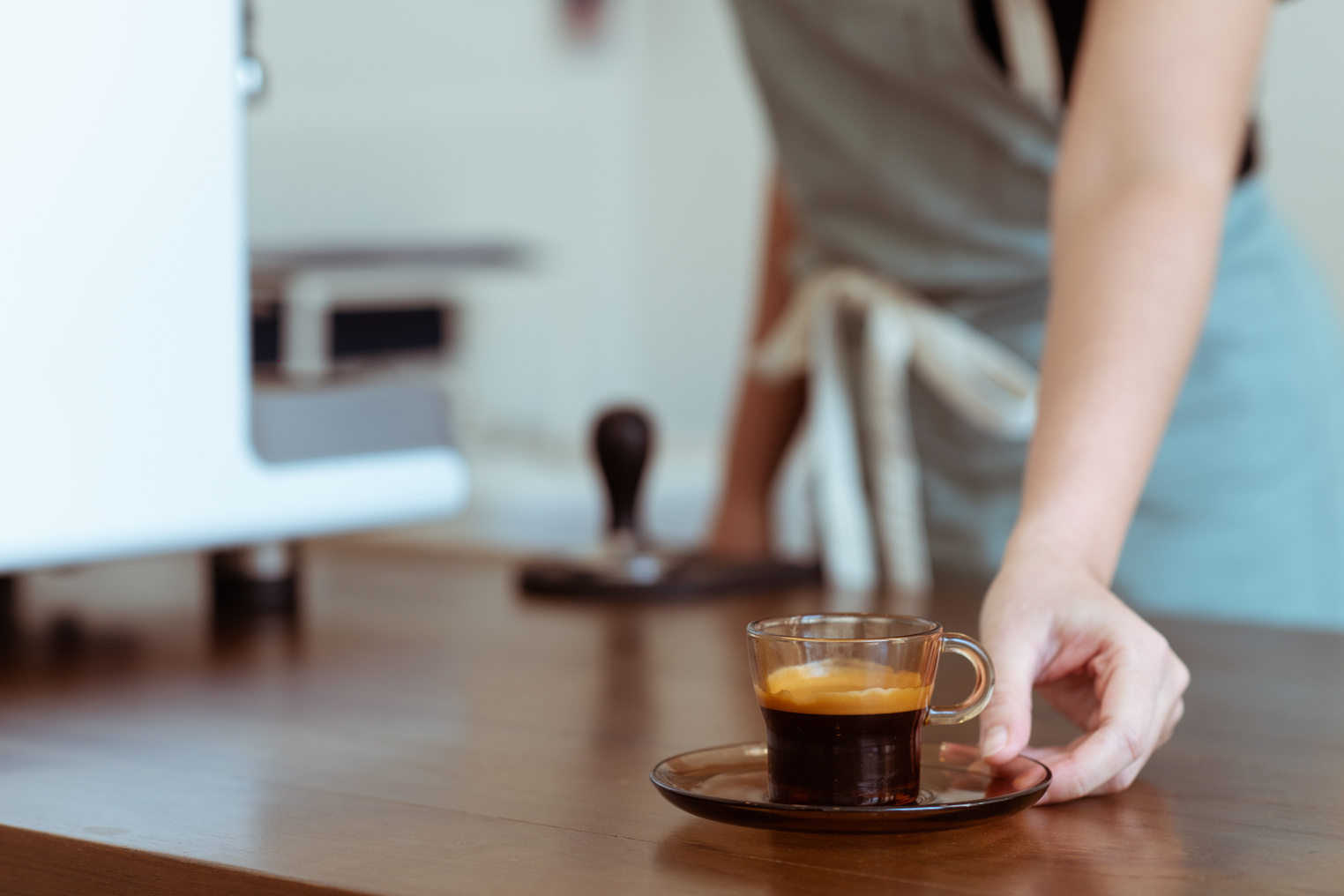 Crop coffee house worker serving cup of freshly brewed espresso